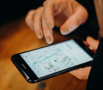 Person, der bruger en smartphone til at finde virksomhedens placering på Google Maps, som en del af optimering via Google My Business.